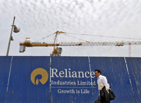 FILE PHOTO - A man walks past an advertisement of Reliance Industries Limited at a construction site in Mumbai, India, May 14, 2015. REUTERS/Shailesh Andrade/File Photo