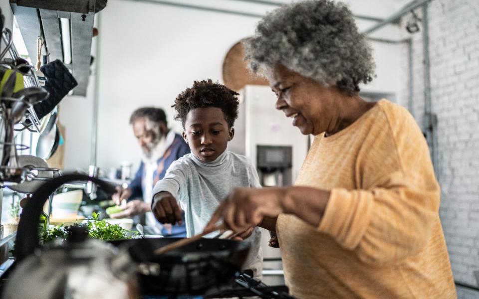 Grandson helping his grandmother cooking at home