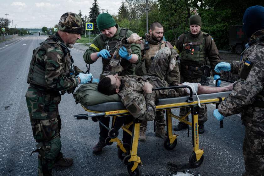 Members of the Ukrainian Army's mobile evacuation unit treat a wounded soldier before his transfer to a hospital by ambulance, on a road near Lysychansk, eastern Ukraine, on May 10, 2022, amid the Russian invasion of Ukraine. (Photo by Yasuyoshi CHIBA / AFP) (Photo by YASUYOSHI CHIBA/AFP via Getty Images)