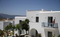 A worker cleans the balcony of a hotel room in Agios Prokopios village, on the Aegean island of Naxos, Greece, Wednesday, May 12, 2021. Greece Friday became the latest country to open up its vacation season as it dismantles lockdown restrictions and focuses its vaccination program on the islands. (AP Photo/Thanassis Stavrakis)