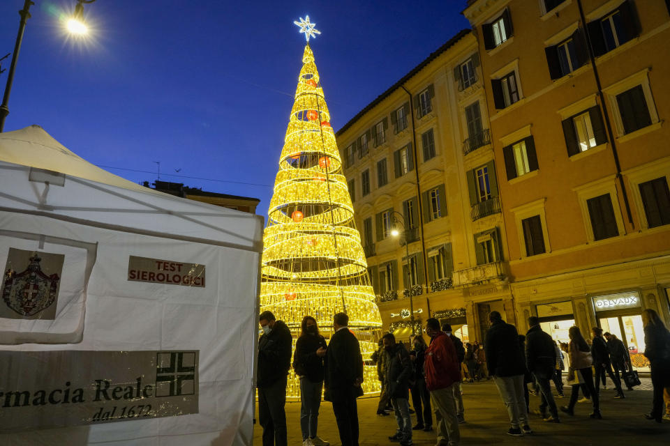 People line up at a rapid swab testing site in Rome, Thursday, Dec. 30, 2021. Italy surged to a record 98,030 new cases of COVID-19 infections Thursday, an increase of 25% in one day. The government was meeting later to consider reducing the quarantine for vaccinated people, amid forecasts that the increasing numbers of infections could place more than 2 million people in quarantine after close contact with infected people. (AP Photo/Andrew Medichini)