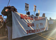 Demonstrators gather to block a road at the base of Hawaii's tallest mountain, Monday, July 15, 2019, in Mauna Kea, Hawaii, to protest the construction of a giant telescope on land that some Native Hawaiians consider sacred. (AP Photo/Caleb Jones)