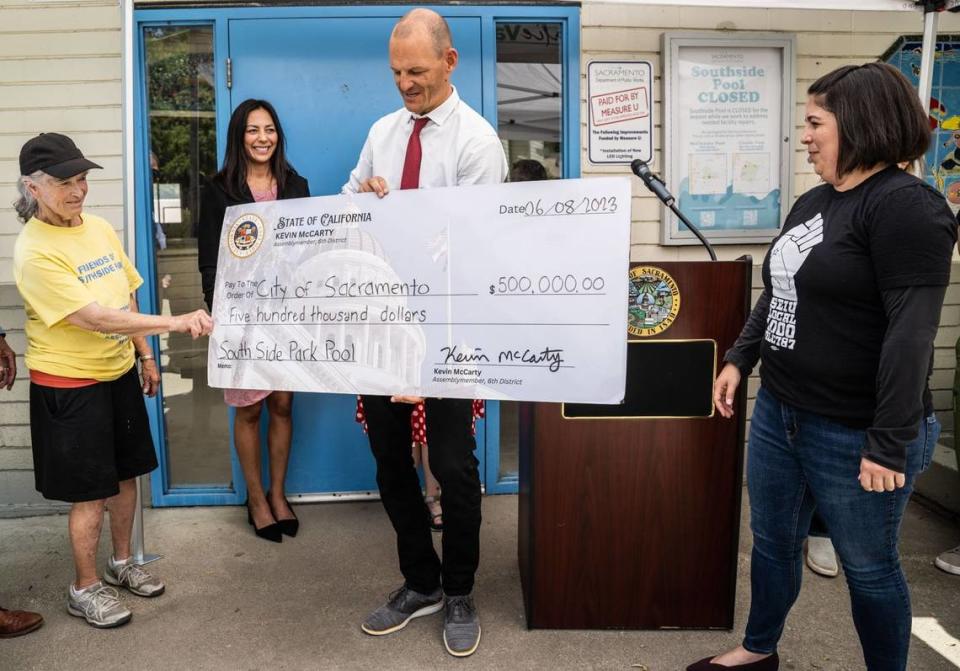 Southside Park Neighborhood Association member Marni Leger helps Assemblyman Kevin McCarty, D-Sacramento, hold a replica check on Wednesday, June 8, 2023, for $500,000 from the state to help reopen the closed Southside Park pool. Recreation manager Jackie Beecham and Councilwoman Katie Valenzuela, right, join in the announcement. The pool will be closed this summer until the project is complete.