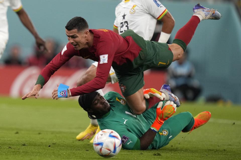 Portugal's Cristiano Ronaldo, top, runs over over Ghana goalkeeper Lawrence Ati-Zigi during a match on Thursday.