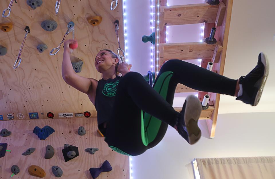 Whitney Miller of Wilmington, a former "American Ninja Warrior" contestant, hangs from a set of ninja grips in her basement training area.