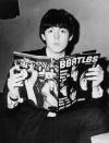 <p>Holding a Beatles fan magazine in 1964. </p>