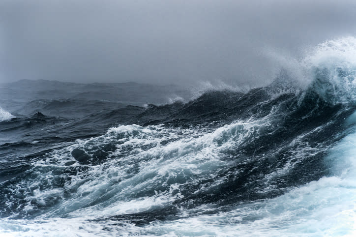 A rough sea with large, frothy waves under an overcast sky