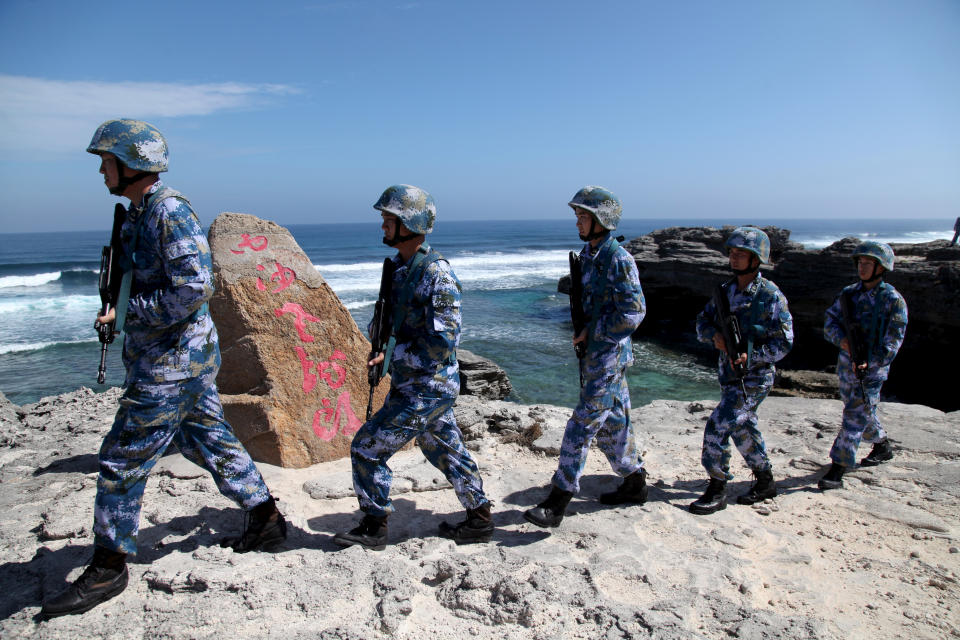 Soldiers of China's People's Liberation Army (PLA) Navy patrol at Woody Island, in the Paracel Archipelago, which is known in China as the Xisha Islands, January 29, 2016. The words on the rock read, 