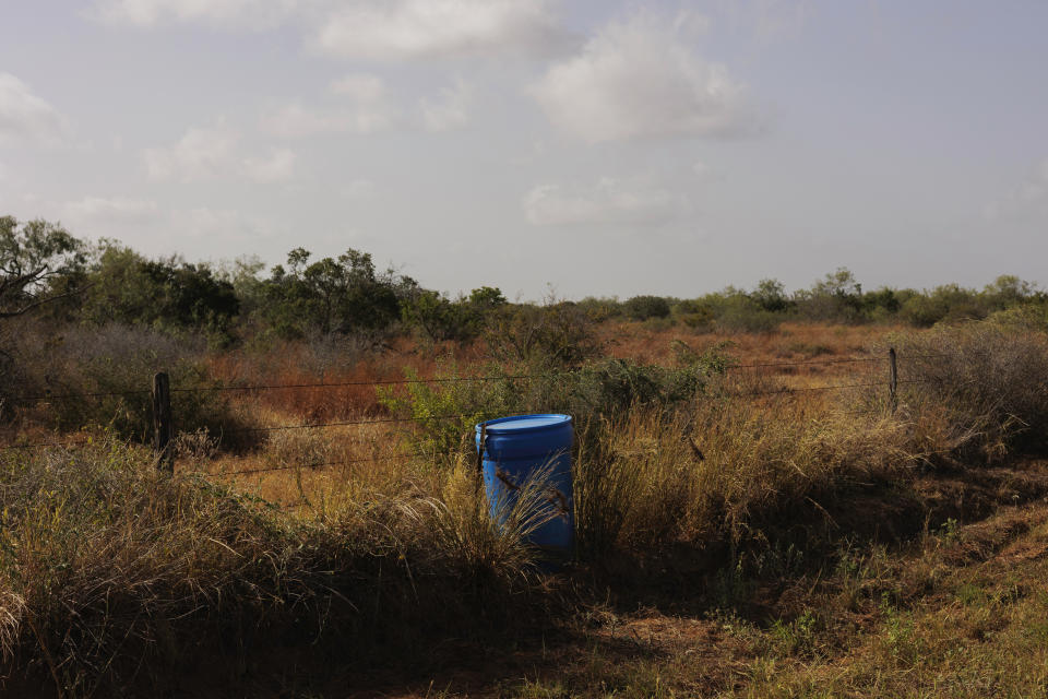 A water station for immigrants containing sealed jugs of fresh water sits along a fence line near a roadway in rural Jim Hogg County, Texas, Tuesday, July 25, 2023. The South Texas Human Rights Center maintains over 100 blue barrels consistently stocked with water across rural South Texas to serve as a life-saving measure for immigrants who have crossed into the United States to travel north in the sweltering heat. (AP Photo/Michael Gonzalez)