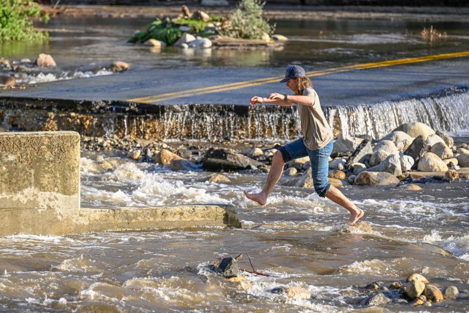 Finn Welch of Three Rivers hops between river rocks and bridge elements Monday, March 13, 2023 at the South Fork Drive bridge. Fair weather brought many out to see damages caused by recent storms.