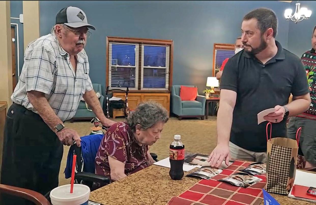 Christopher Overly-McDowell, right, on Dec. 25, 2023 shows photos and presents information he gathered to his mother, Linda Overly, seated, on her brothers and sisters and her birth parents. Linda Overly was fostered as a child and separated from her siblings, who were adopted.