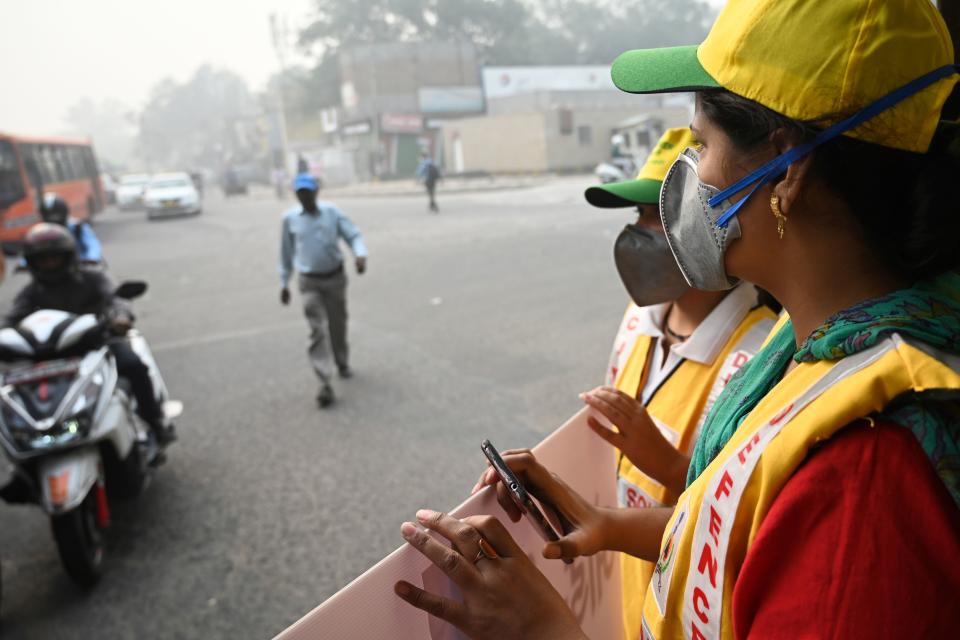 Volunteers from civil defence display a placard to aware drivers on a street after the local government ordered half of the city's private cars to be taken off the road based on an odd-even registration plate system to help reduce air pollution, in New Delhi on Nov. 4, 2019. (Photo: Money Sharma/AFP via Getty Images)