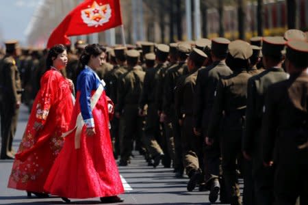 Women wearing traditional clothes walk past North Korean soldiers after an opening ceremony for a newly constructed residential complex in Ryomyong street in Pyongyang, North Korea April 13, 2017.  REUTERS/Damir Sagolj