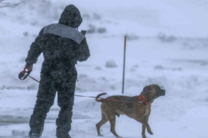 A man takes pictures as he walks with his dog in the snow in Altoona, Iowa, on Friday. Photo by Tannen Maury/UPI