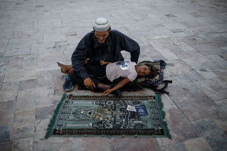 A man holding a child begs for money as he sings religious songs in Stara Carsija (Old Bazaar) part of central Skopje, Macedonia, May 31, 2018. REUTERS/Marko Djurica