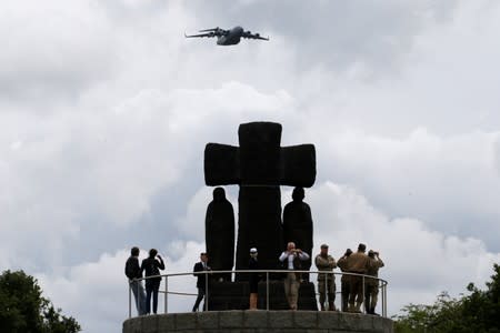 A plane flies over a cross of La Cambe German war cemetery during a remembrance ceremony in La Cambe in Normandy as France prepares to commemorate the 75th anniversary of the D-Day