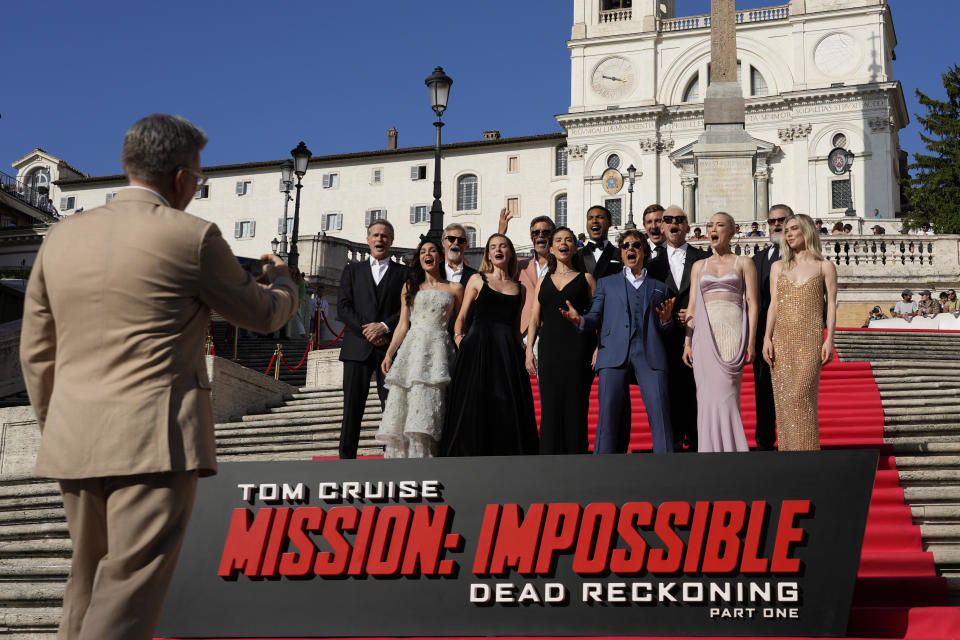 Director Chris McQuarrie, left, takes a photo of the cast on the red carpet of the world premiere for the movie "Mission: Impossible - Dead Reckoning" at the Spanish Steps in Rome Monday, June 19, 2023. (AP Photo/Alessandra Tarantino)