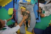 A physiotherapist exercises five-month-old Laura during an evaluation session at the Casa da Esperanca Hospital (Hope House Hospital) in Santos, Sao Paulo state, Brazil April 20, 2016. REUTERS/Nacho Doce