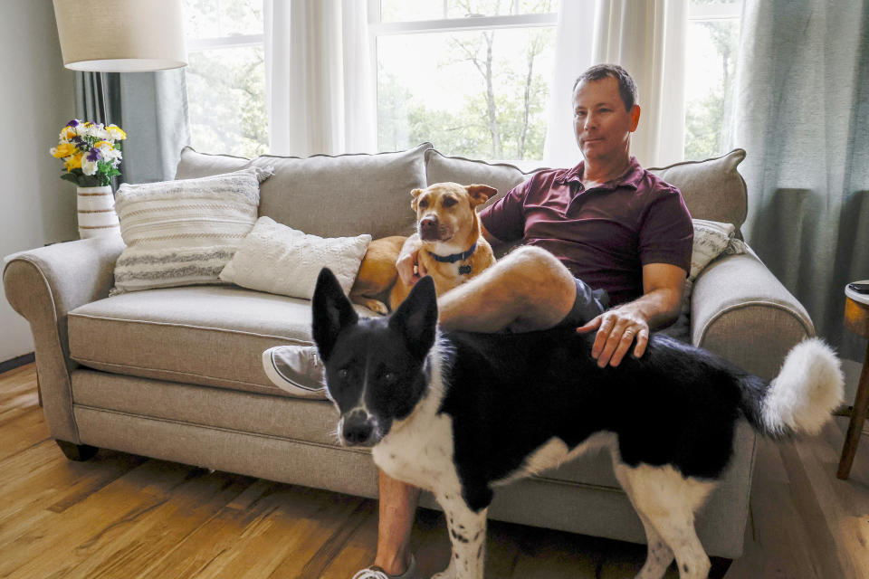 Phil Durst sits with his dogs in Homewood, Ala., on Tuesday, Aug. 15, 2023. Durst underwent an experimental procedure that aims to treat severe injuries in one eye with stem cells from the other. “I went from completely blind with debilitating headaches and pondering if I could go another day — like really thinking I can’t do this anymore" to seeing well enough to drive and emerging from dark places literally and figuratively, he says. (AP Photo/Butch Dill)