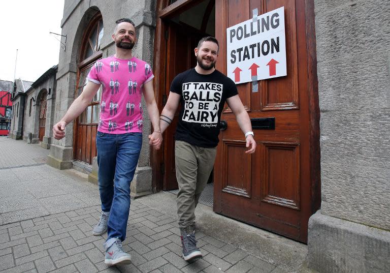 A couple pose holding hands as they walk out of a polling station after voting in Drogheda, north of Dublin on May 22, 2015