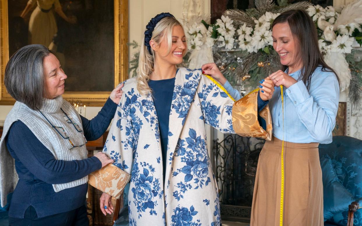 A model wearing a handmade Delft blue floral kimono coat with a gold brocade cuff, made from material that used to adorn rooms at Buckingham Palace and Windsor Castle