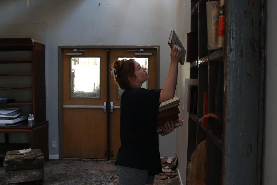 Jackie Skelding, owner of Rare Bird Interiors, helps pack up books in Talquin Trading Co. in Railroad Square. The Tallahassee art district was badly damaged by a tornado and severe storms Friday morning.