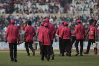 Groundsmen wearing pink shirt, commemorating first pink ball match, clear the ground during the first day of the second test match between India and Bangladesh, in Kolkata, India, Friday, Nov. 22, 2019. (AP Photo/Bikas Das)