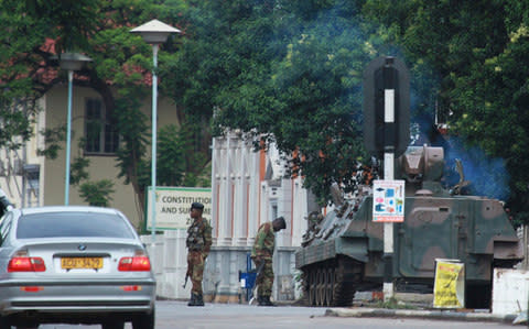 A military tank is seen with armed soldiers on the road leading to President Robert Mugabes office in Harare - Credit: AP
