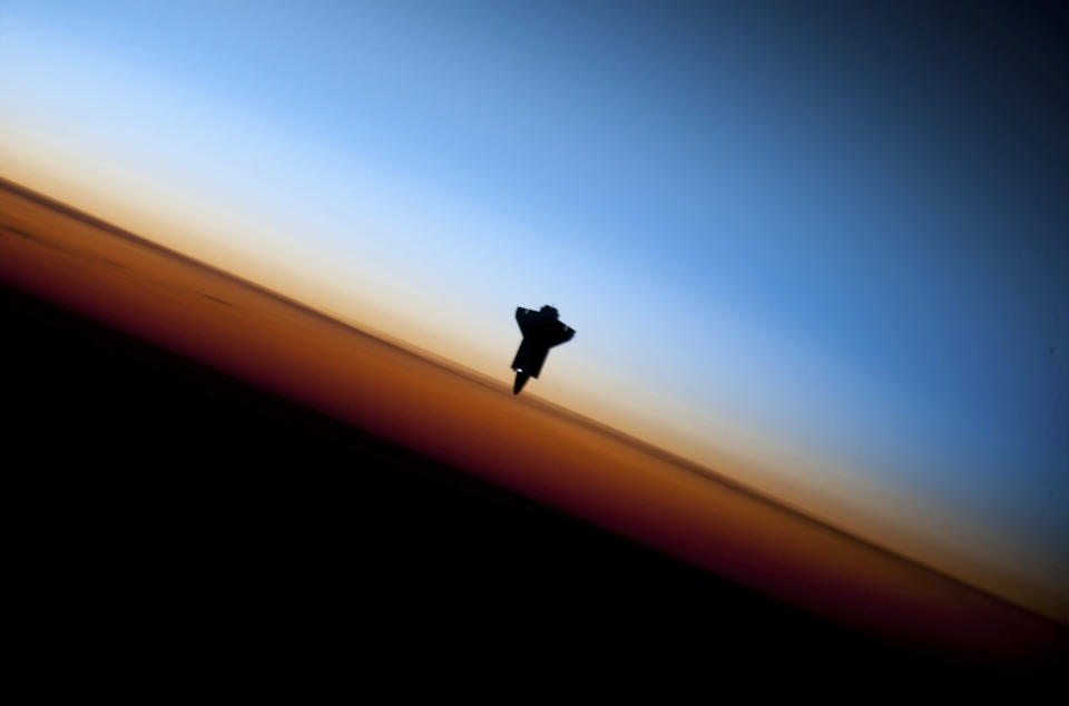 The space shuttle Endeavour is silhouetted against the backdrop of Earth's horizon prior to docking with the International Space Station in this picture taken by an Expedition 22 crew member on February 9, 2010 and released by NASA February 12, 2010.