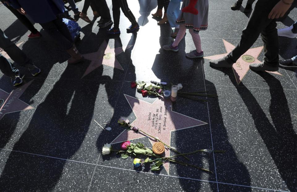 People walk past an impromptu memorial created on a blank Hollywood Walk of Fame star by fans of late actress and author Carrie Fisher, who does not have an official star on the world-famous promenade, in Los Angeles Wednesday, Dec. 28, 2016. Paste-on letters spell out her name and the phrase "May the force be with you always. Hope" (AP Photo/Reed Saxon)