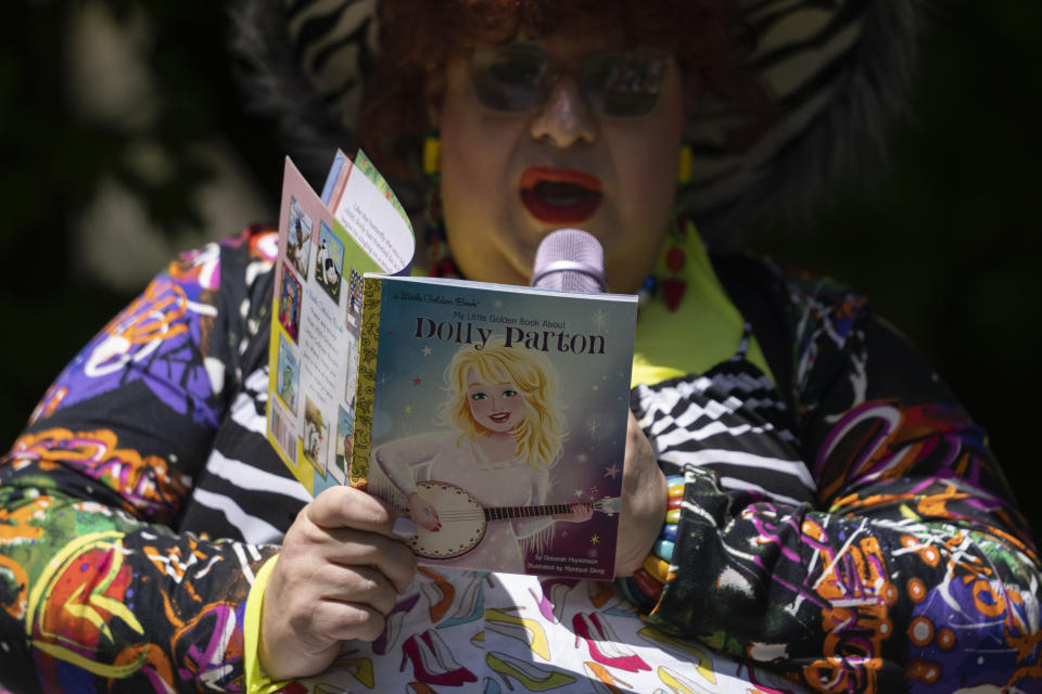 La drag queen Alexus Daniels lee "My Little Golden Book About Dolly Parton" a niños durante la actividad "Drag Storytime!" en Mt. Carmel, Pensilvania, en el jardín en Pink Moon Collective, el sábado 6 de mayo de 2023. (Foto AP/Carolyn Kaster)