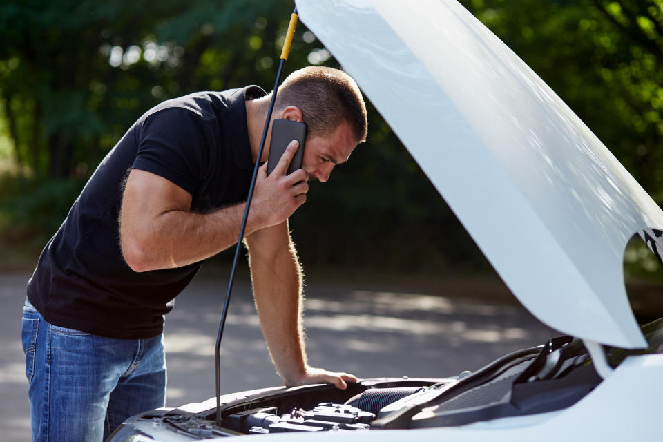 Homme appelant quelqu'un à l'aide avec sa voiture cassée