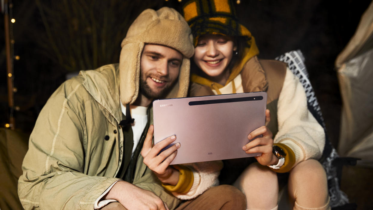  Samsung Galaxy Tab tablet being used by two young people, one a man, the other a woman, sat down at night outdoors 