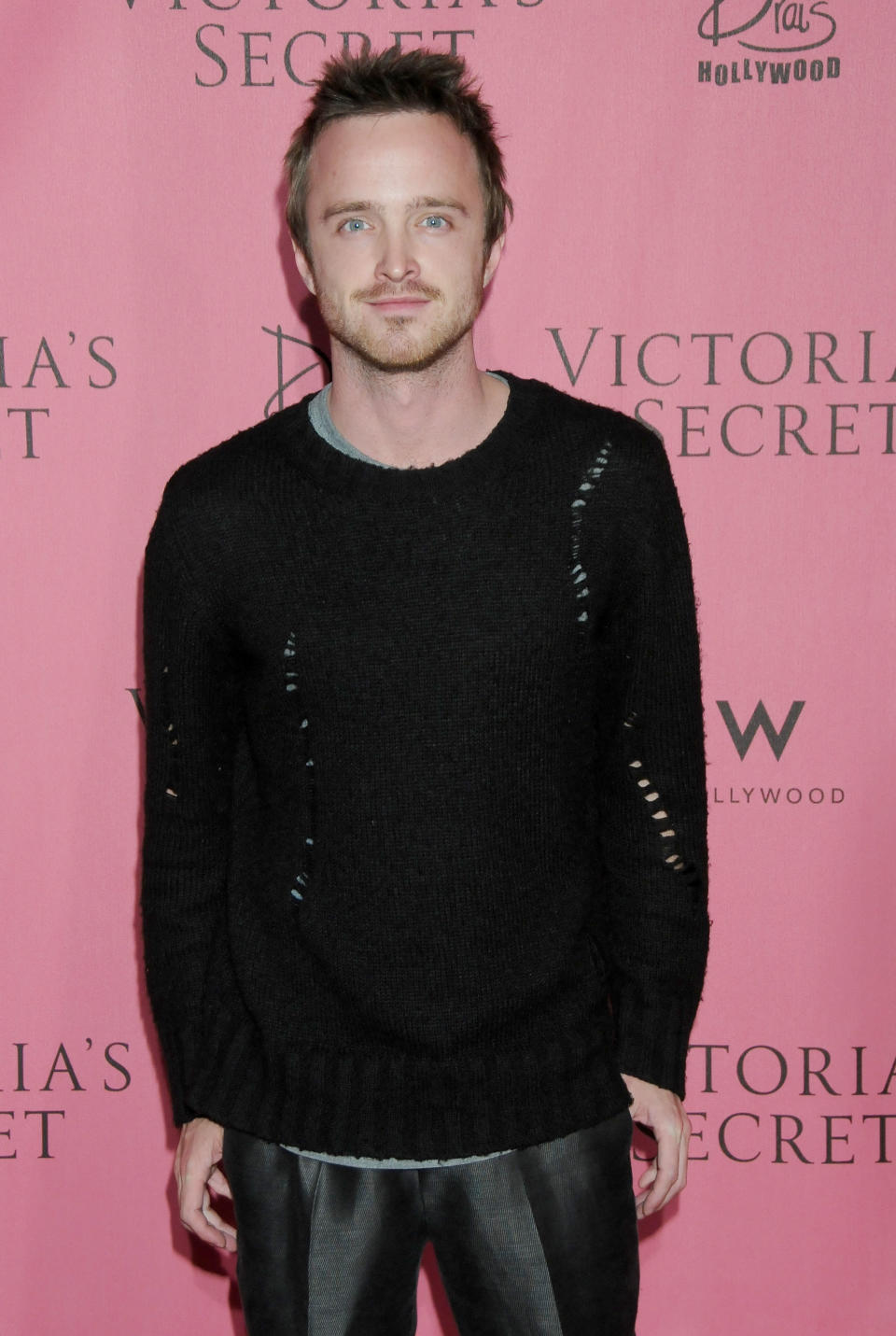 Aaron Paul poses in a ripped sweater on the red carpet at a Victoria's Secret event