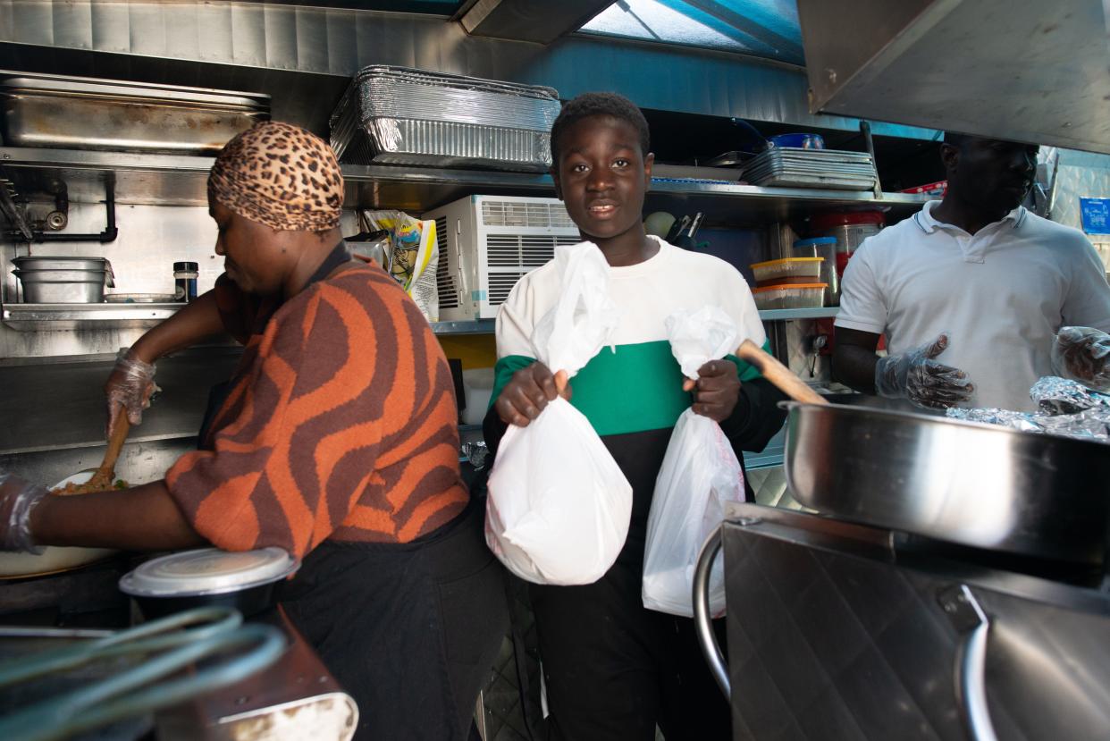 Eric Twum-Barimah, 14, delivers orders while his parents, Millicent, left, and Isaac make orders Thursday at KononiaTouch African Cuisine.