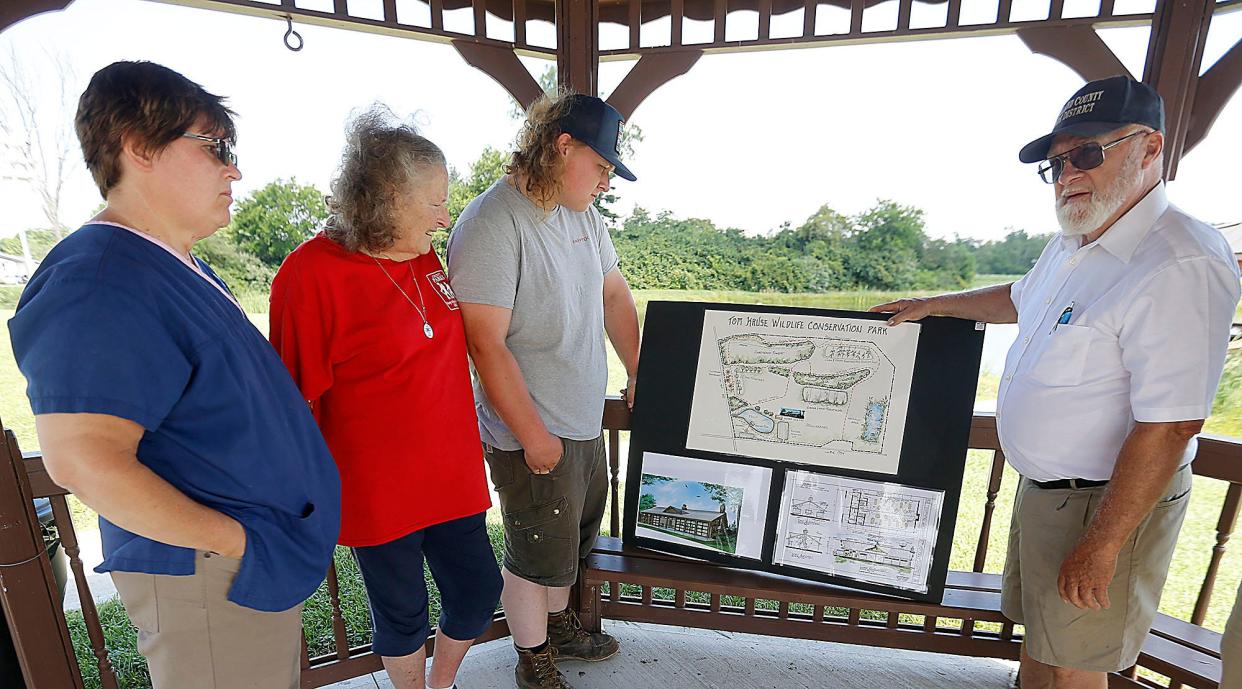Marnie McClure, Peggy McClure, Christopher McClure and Andy McClure look over the renderings for the Davy McClure Outdoor Educational Center at Tom Kruse Park in July 2022. (TIMES-GAZETTE FILE PHOTO)