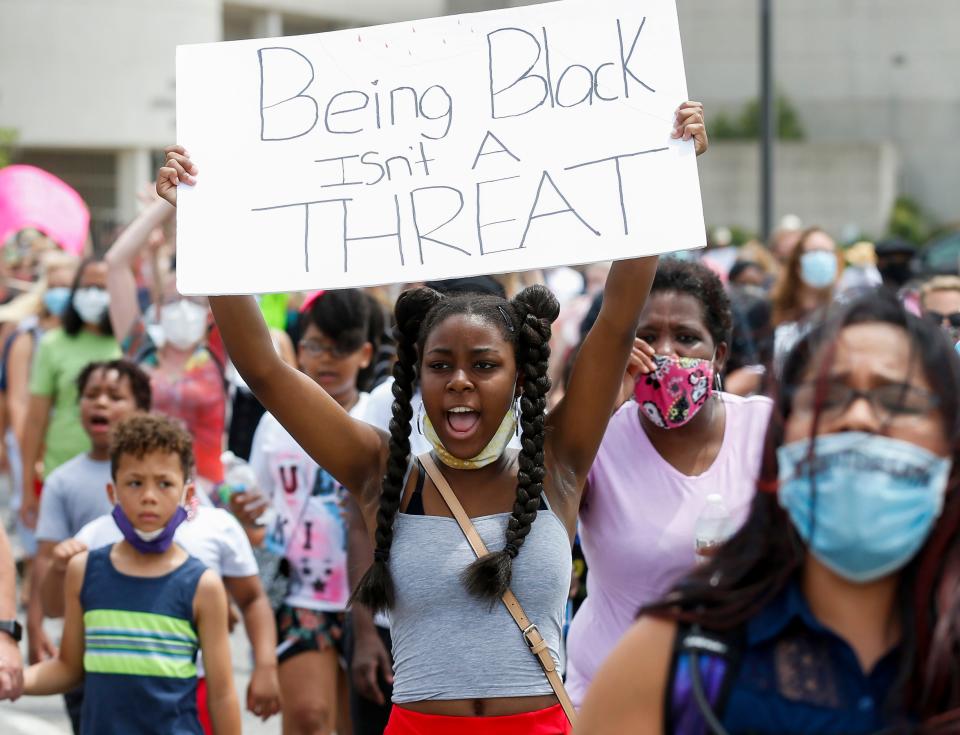 Nakyra Smith, 14, holds up a sign that says, "Being Black Isn't A Threat" during the Juneteenth Freedom Walk on Saturday, June 27, 2020.