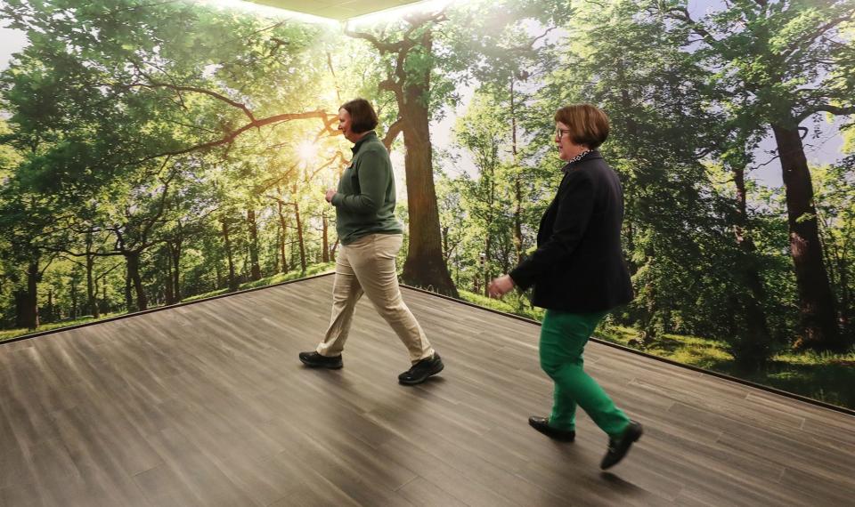 Jennifer Lennox, director of public relations, and Sandra Reid, vice president of corporate communications and strategic planning at The Davey Tree Expert Company, walk past what Lennox refers to as the Instagram wall during a tour.