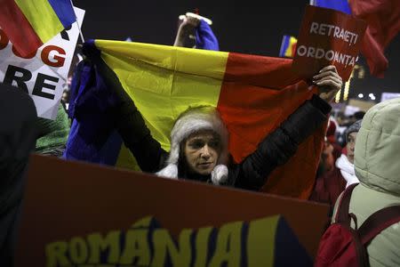 A protester holds a Romanian national flag during a demonstration in Bucharest, Romania, February 3, 2017. REUTERS/Stoyan Nenov