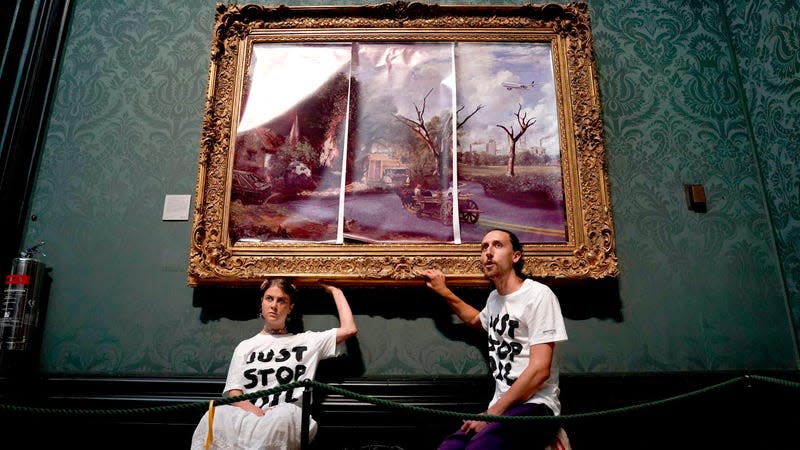 Protesters from Just Stop Oil climate protest group glue their hands to the frame of John Constable’s The Hay Wain after first having covered the painting with their own picture at the National Gallery, London, on December 20, 2022. 