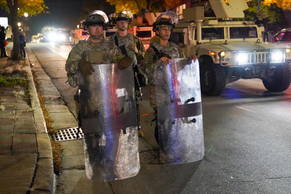 CORRECTS TO JOHN CHISHOLM NOT JOHN CHISOLM - National Guardsmen in riot gear stand in the street Friday, Oct. 9, 2020, in Wauwatosa, Wis. On Wednesday, District Attorney John Chisholm refused to issue charges against Wauwatosa Police Officer Joseph Mensah for the Feb. 2 fatal shooting of 17-year-old Alvin Cole at Mayfair Mall. (AP Photo/Morry Gash)