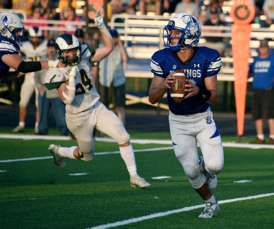 Ryan Zanger of Dundee rolls out with pursuit from Teigan Donovan of  Flat Rock in the first half Thursday, August 24, 2023.