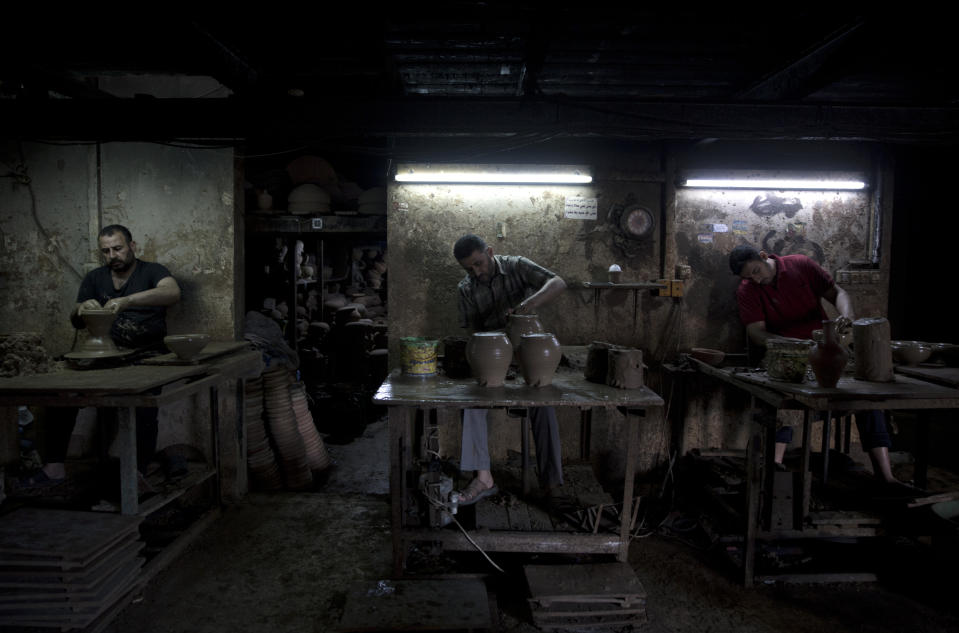 In this Saturday, July 6, 2019 photo, Palestinians, work at a pottery workshop in Gaza City.Talk about old Gaza, and what pops up are images of clay pottery, colorful glassware, bamboo furniture and ancient frame looms weaving bright rugs and mats. As such professions could be dying worldwide, the pace of their declining is too fast in Gaza that out of its some 500 looms, only one is still functioning. (AP Photo/Khalil Hamra)