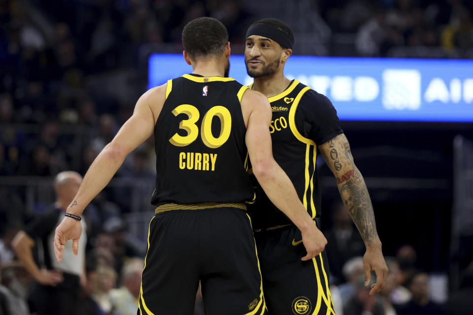 Golden State Warriors guards Gary Payton II, right, and Stephen Curry (30) celebrate during the first half of an NBA basketball game against the Phoenix Suns in San Francisco, Saturday, Feb. 10, 2024. (AP Photo/Jed Jacobsohn)