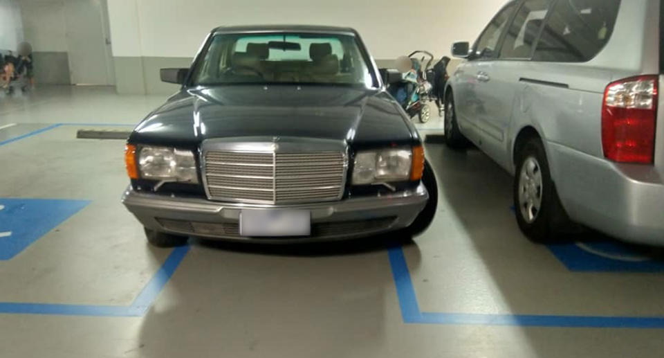 The Mercedes is seen taking up two disability parking spaces at a Melbourne hospital. A photo of the car from the front with a child in a walker behind it.