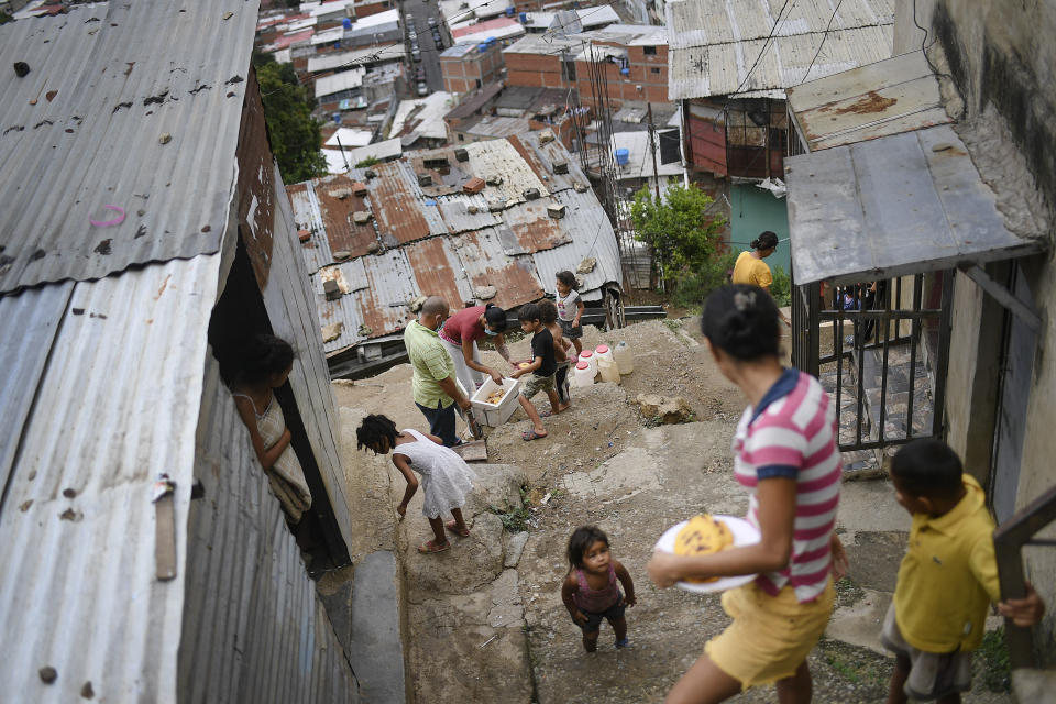 Los residentes reparten tortas de harina de maíz conocidas localmente como arepas en la comunidad Altos de Lidice de Caracas, Venezuela, el sábado 5 de junio de 2021, en medio de la pandemia de coronavirus. (AP Foto/Matías Delacroix)