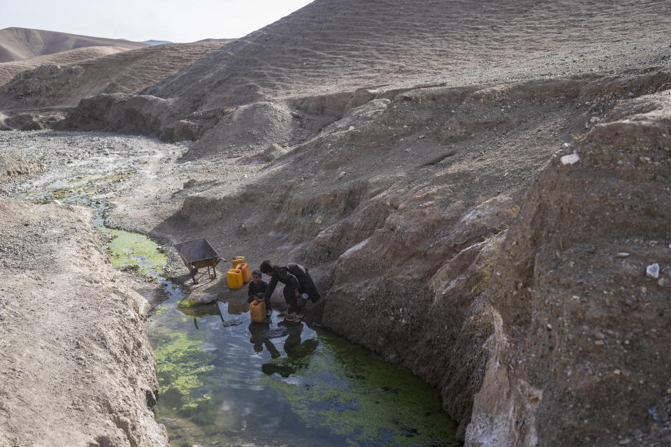 Two brothers fill canisters with water from a stagnant pool about 3 kilometers (2 miles) from their home in Kamar Kalagh village outside Herat, Afghanistan, Friday, Nov. 26, 2021. Afghanistan’s drought, its worst in decades, is now entering its second year, exacerbated by climate change. (AP Photo/Petros Giannakouris)