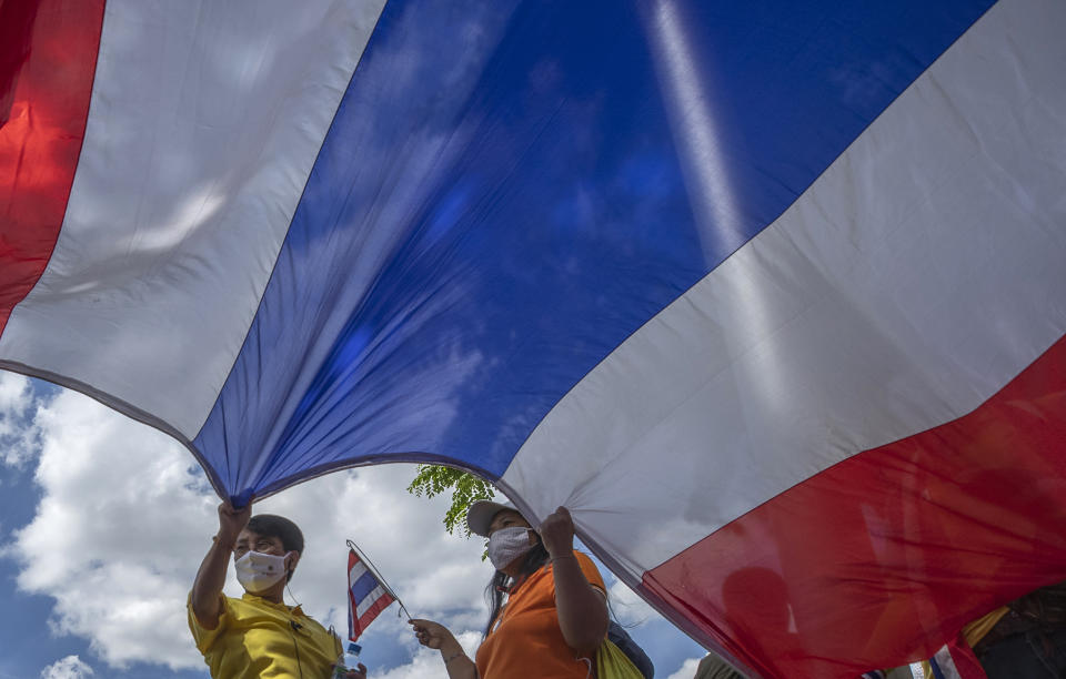 Supporter of Thailand's monarchy lift a giant national flag during a gathering stating their concern over the country's pro-democracy movement which they feel besmirches the royal institution in Bangkok, Thailand, Thursday, July 30, 2020. The demonstration was held at Democracy Monument, a traditional venue for protests of all political stripes that in recent weeks has hosted several larger pro-democracy, anti-government protests organized by students. (AP Photo/Sakchai Lalit)