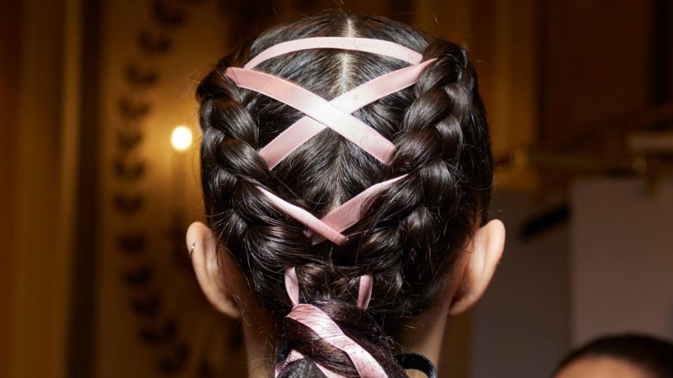 Model with braided bun, woven with criss-cross pink bows at Christian Siriano SS24 