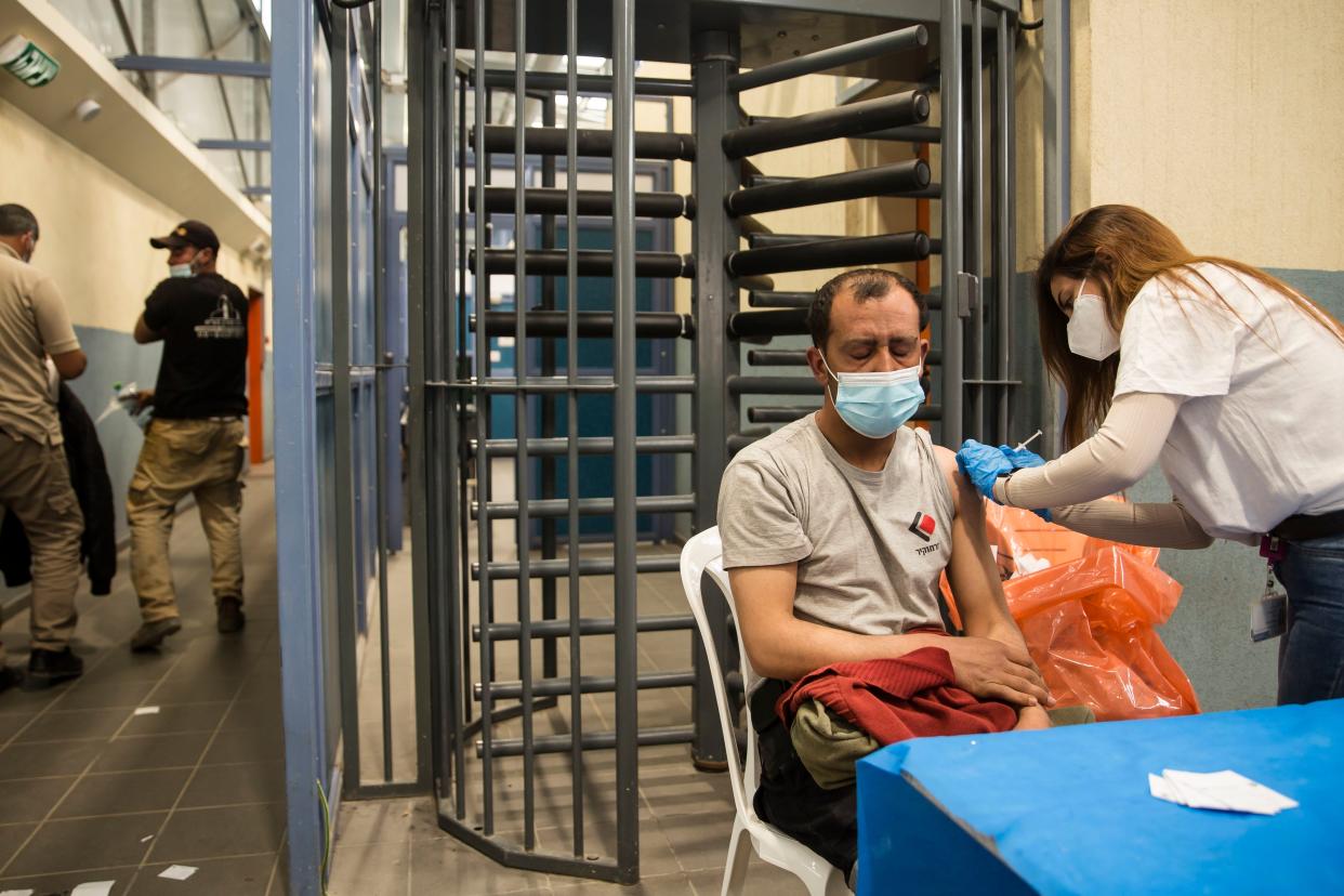 A Palestinian man who works in Israel receives the first dose of a Moderna COVID-19 vaccine by an Israeli medical worker in Meitar crossing checkpoint between the West Bank and Israel on March 9, 2021, in Meitar, Israel.